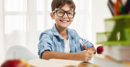 high-angle-smiley-boy-with-glasses-studying