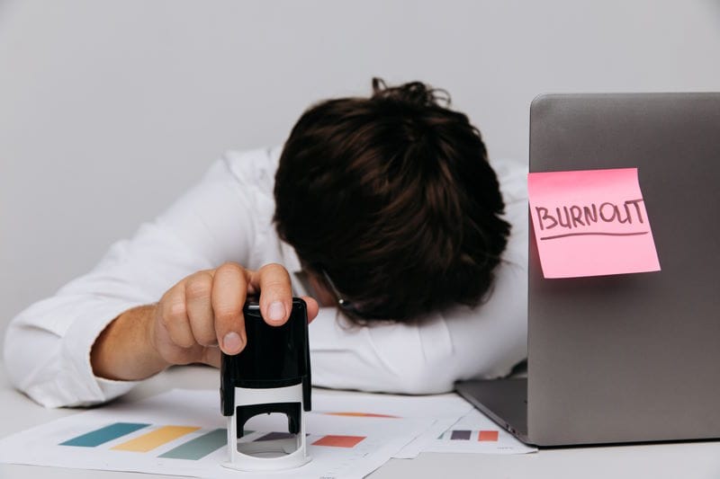 Man lays in office with stamp in his hand. Burnout syndrome concept.